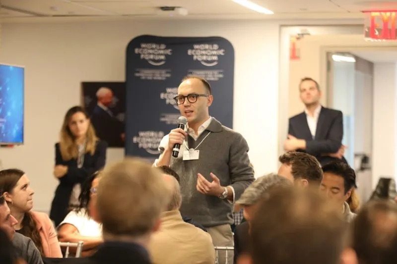 Sercan Esen speaking into a microphone at the World Economic Forum's Innovator Communities Meeting, New York, November 2023